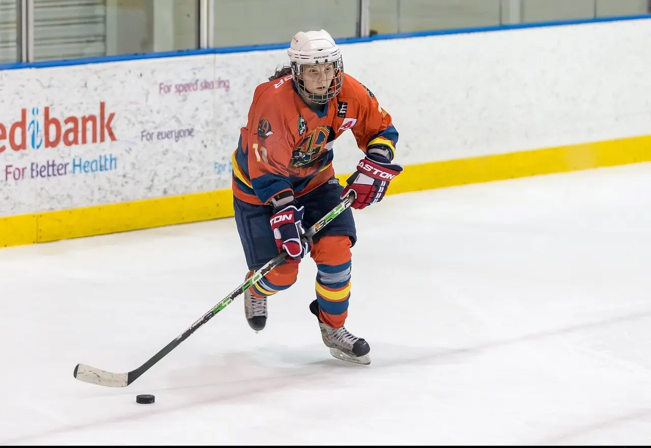 Ishockeyspiller i orange trøje med puck