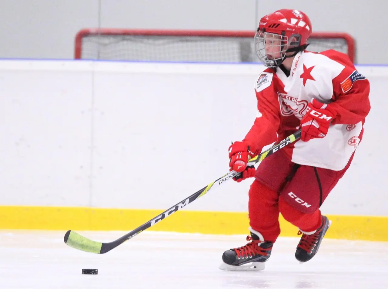 Ishockeyspiller i rød og hvid dragt med puck